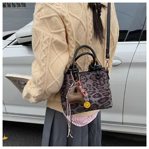 Detail of leopard print suede crossbody bag featuring leather handles and cute charms