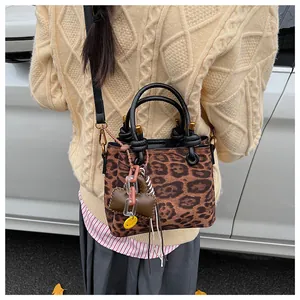 Close-up of leopard print suede crossbody bag with heart charms and yellow smiley tag