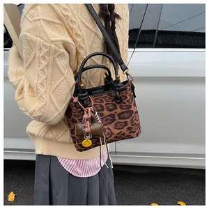 Detail of leopard print suede handbag featuring a yellow smiley face charm and black strap