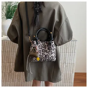 Detail shot of a leopard print crossbody bag with charms and detachable black shoulder strap