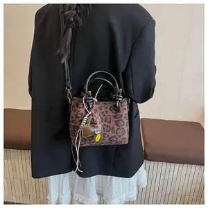 Detail of leopard print handbag with heart charm shown on model in black blazer