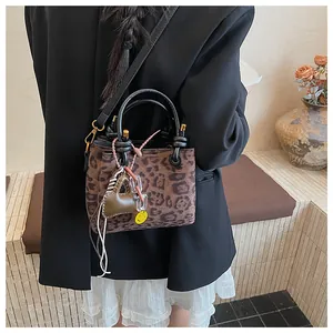 Detail of leopard print suede handbag with heart and smiley face charms on a model