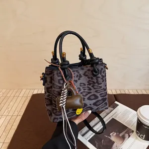 Vintage leopard print suede handbag with knotted handles and plush bone charm detail