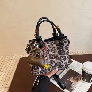 Chic leopard print faux suede handbag with black round handles and luxury charms