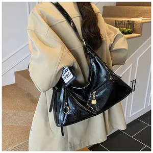 Detail of glossy oil-wax leather texture and gold hardware on black hobo shoulder bag