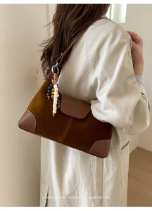 Detail of dark brown suede and leather crossbody bag with chic wooden bead tassels