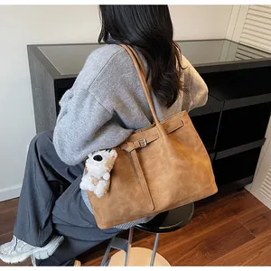 Detalle de bolso tote marrón con hebilla decorativa y llavero de perrito de peluche