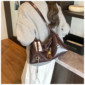 Detail view of deep brown glossy patent leather shoulder bag with vintage pleats and metal ring