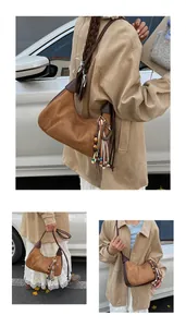 Détail du sac croissant en daim marron avec pompons en cuir et perles de bois colorées