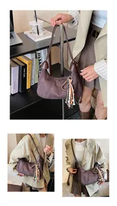 Détail du sac croissant en daim marron foncé avec garniture en cuir et gland en perles