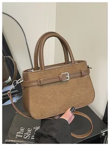 Detail of brown bucket bag showing suede and synthetic leather patchwork with strap accent