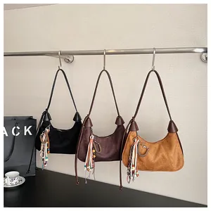 Détails de trois sacs demi-lune en daim de couleurs noir, marron foncé et jaune moutarde