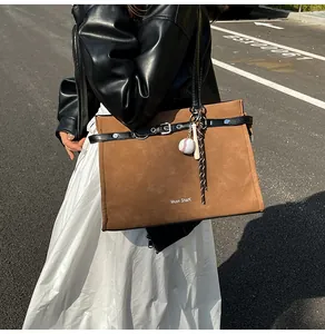 Detail of caramel suede tote bag with decorative baseball bat charm and woven rope accent
