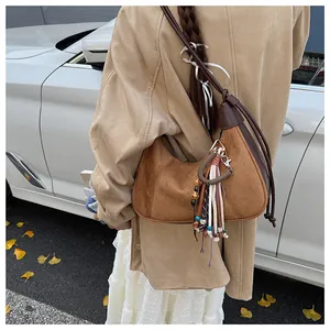 Sac hobo en daim marron avec pampilles colorées et bandoulière fine en cuir en extérieur
