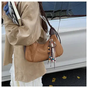 Gros plan sur un sac hobo en daim marron avec pampille ethnique perlée et détails