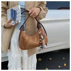 Détail du sac hobo en daim vintage avec breloque en perles et accents de franges