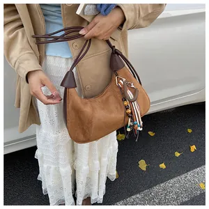 Détail d'un sac demi-lune en daim marron avec breloque à glands bohème et sangle