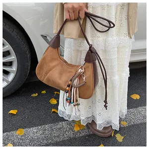 Vue détaillée d'un sac hobo en daim marron avec glands bohèmes et tenue d'automne