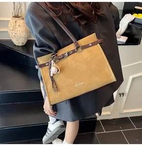 Detailed back view of a mustard yellow tote bag with brown trim and sports pendant