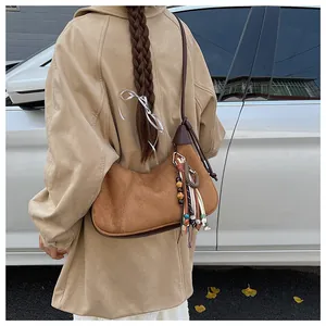 Sac hobo en daim marron avec glands ethniques et détails tressés sur l'épaule