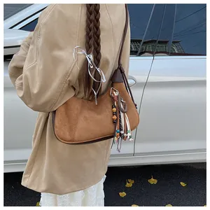 Détail d'un sac hobo en daim marron avec pendentif à franges ethnique et bords en cuir