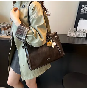 Close-up of retro brown leather tote with fine stitching and sports theme charms
