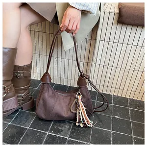 Détail du sac dumpling en daim marron vintage avec pendentif bohème à pompons