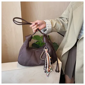 Détails du sac en daim marron foncé avec pompons ethniques et accents en métal bronze