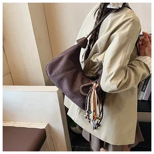 Détail du sac demi-lune en daim marron foncé avec anneau en métal et pompon perlé coloré