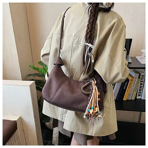 Détail d'un sac hobo en daim avec gland en perles ethniques et bandoulière en cuir