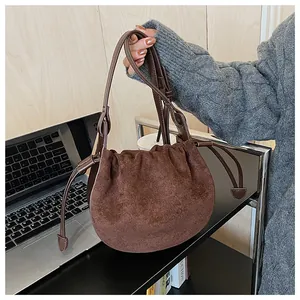 Détail d'un sac nuage en daim marron foncé avec cordon de serrage et plis élégants