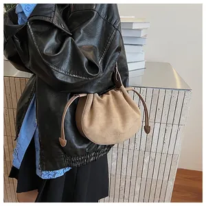 Détail du sac croissant en daim plissé avec logo embossé et texture douce en gros plan