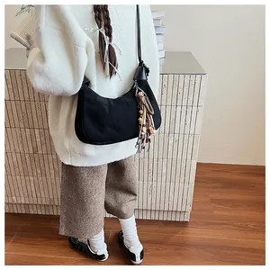 Détail du sac demi-lune en daim noir avec pompons tissés colorés et perles décoratives