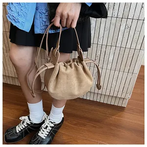 Gros plan d'un sac seau en daim camel avec détails plissés et bandoulière élégante