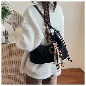Détail du sac hobo en daim noir avec des breloques en perles colorées et des franges