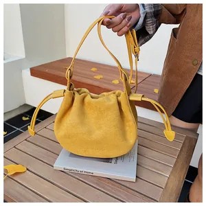 Vue de dessus d'un sac seau en daim jaune vif avec cordon de serrage sur une table en bois