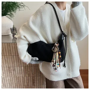 Détail du sac croissant en daim noir avec franges de perles colorées et bandoulière