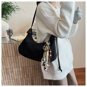Détail du sac demi-lune en toile noire avec pompon bohème coloré et perles en bois