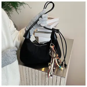 Détail du sac hobo en daim noir avec pendentif ethnique et perles sur une surface en métal