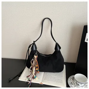 Détail d'un sac hobo en daim noir avec un gland bohème coloré et des perles en bois