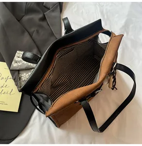 Detail view of large tote bag with brown suede exterior and striped lining with inner pockets