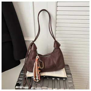 Détail du sac hobo en daim marron foncé avec franges ethniques et pompons décoratifs