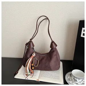 Détail du sac hobo en daim marron foncé avec pompon ethnique et breloques perlées