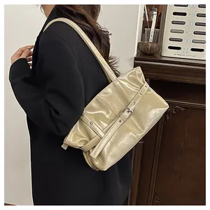 Detail showing glossy cream patent leather underarm bag with decorative metal buckle strap