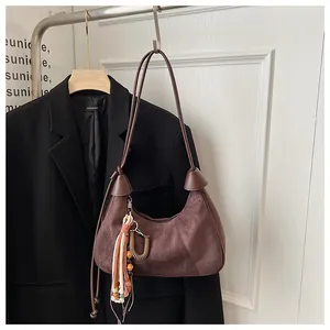 Gros plan détaillé du sac hobo en daim marron avec pendentif à pompon coloré bohème