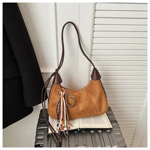 Détail du sac croissant en daim marron avec pompon en perles et breloque en métal