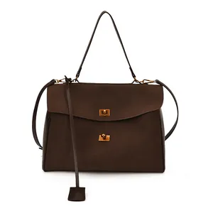 Detail of coffee brown faux suede handbag with gold metal clasp and adjustable strap