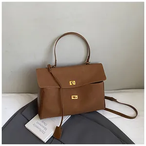 Detail shot of brown leather tote bag featuring gold dual twist locks and top handles