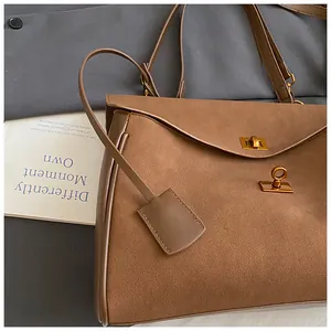 Detail of dark brown faux suede and leather handbag with gold twist lock and metal tag