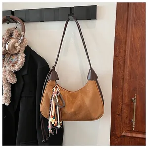 Détail du sac demi-lune en daim camel avec pompon vintage et bordure en cuir